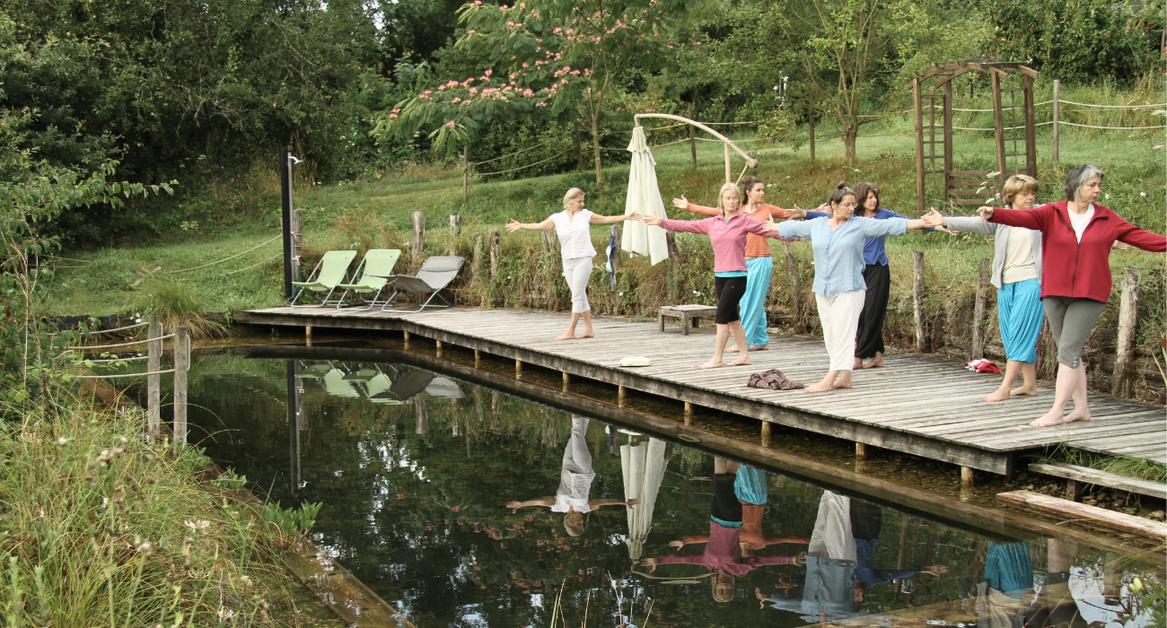 Personne pratiquant le yoga au bord de la piscine naturelle